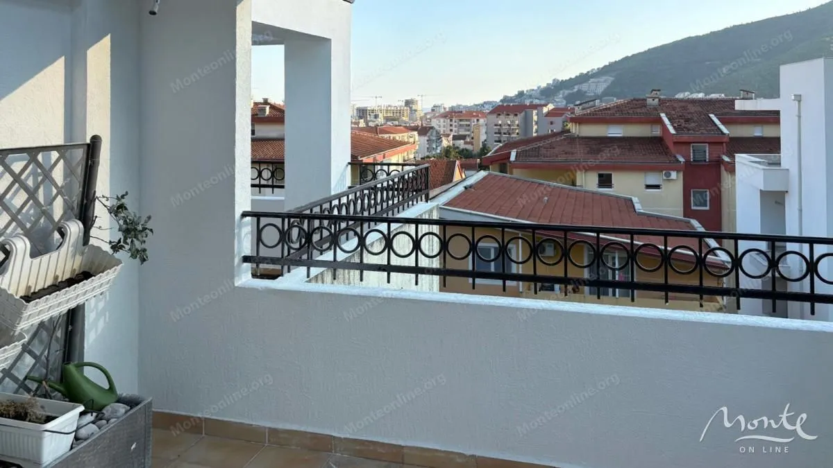 Pogled sa balkona na gradsko naselje i brda u pozadini.