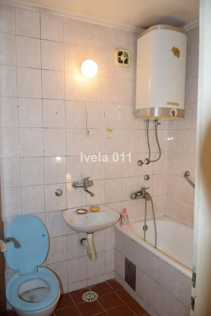 Manje kupatilo sa kadom, umivaonikom i wc šoljom obloženo keramičkim pločicama.