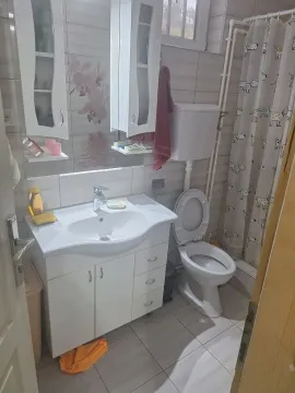 Kupatilo opremljeno umivaonikom sa ormarićem, toaletom i tuš kabinom sa zavesom. - image 4
