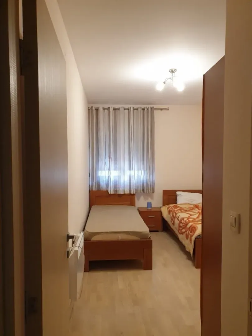 Pogled iz hodnika na spavaću sobu sa dva drvena kreveta.