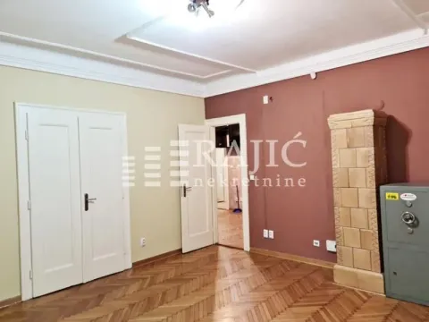Living room with parquet flooring, a tiled stove, and white interior doors. - image 2