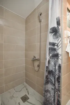 Shower enclosure with beige tiles and a curtain with palm tree motifs. - image 5