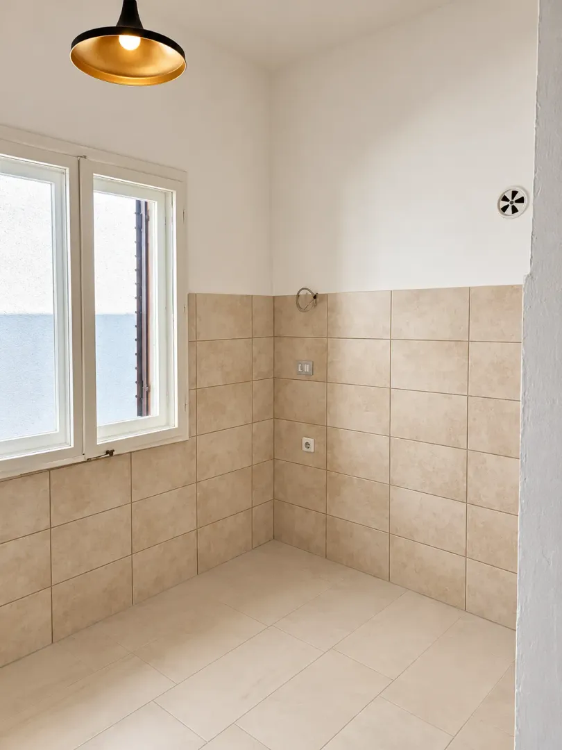 Empty kitchen space with tiled walls and floor.
