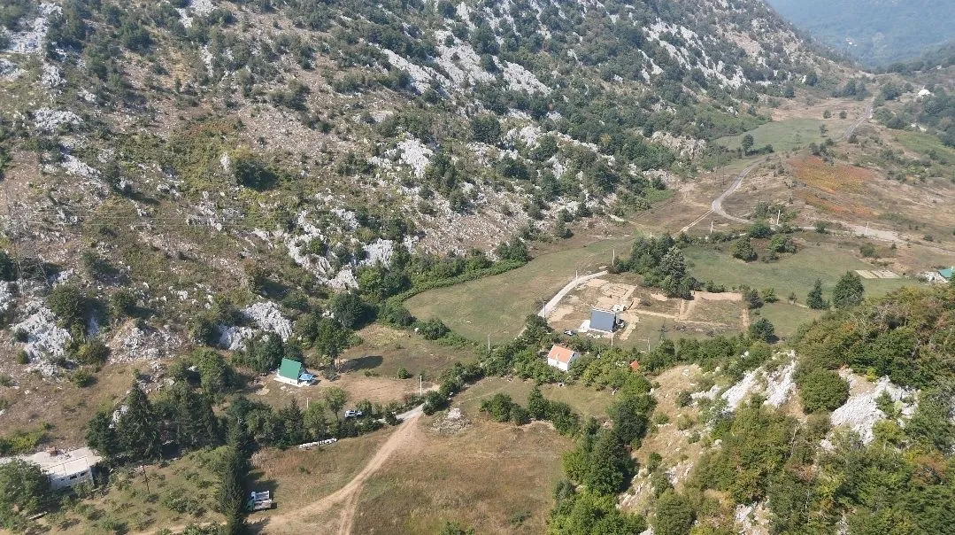 Pogled iz vazduha na planinski predio i seosko imanje sa kućama.