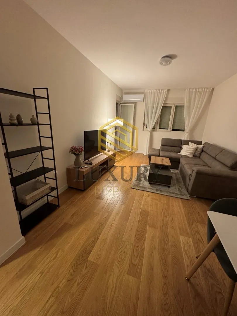 Living room with a sectional sofa, TV, and shelving unit.