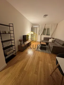 Living room with a sectional sofa, TV, and shelving unit. - image 4