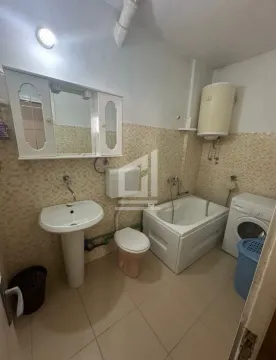 Small bathroom equipped with a sink, bathtub, toilet, and washing machine. - image 8