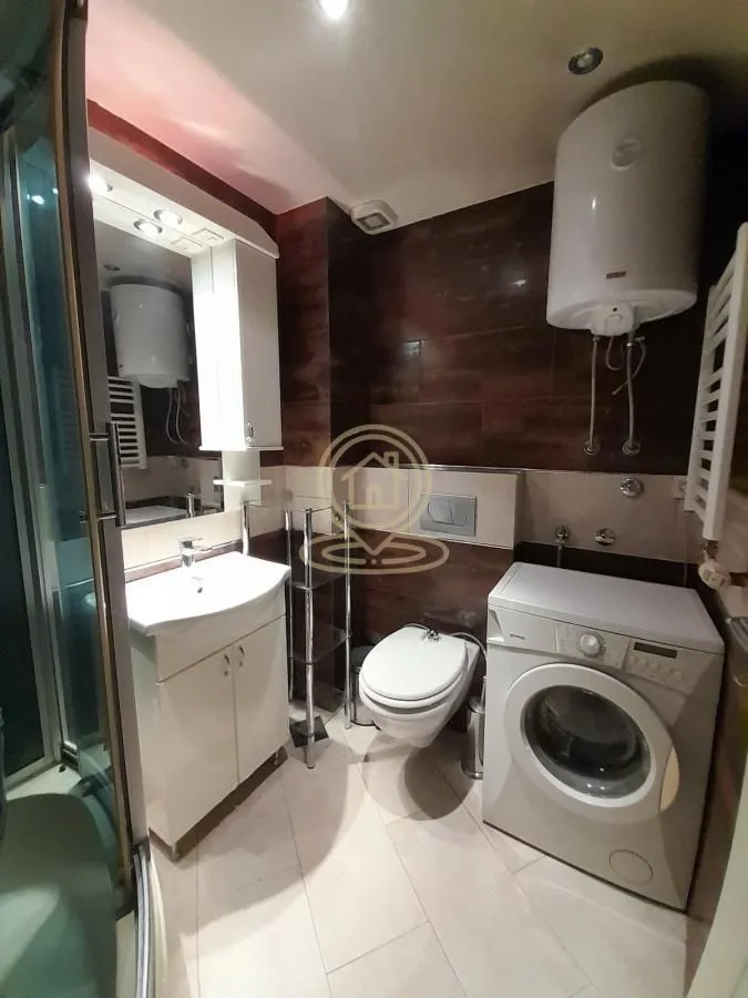 Bathroom equipped with a sink, toilet, shower cabin, and washing machine.
