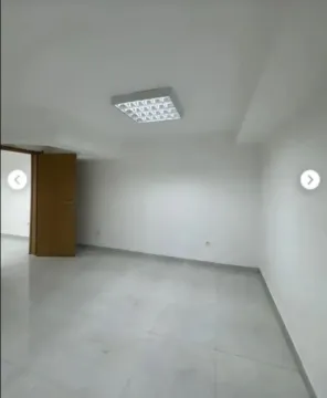 An empty bright room with white walls, tiled floors, and ceiling lighting. - image 10