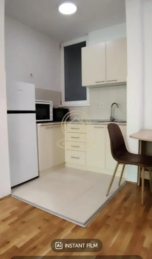 Small kitchen with white cabinets, a refrigerator, and a dining chair.