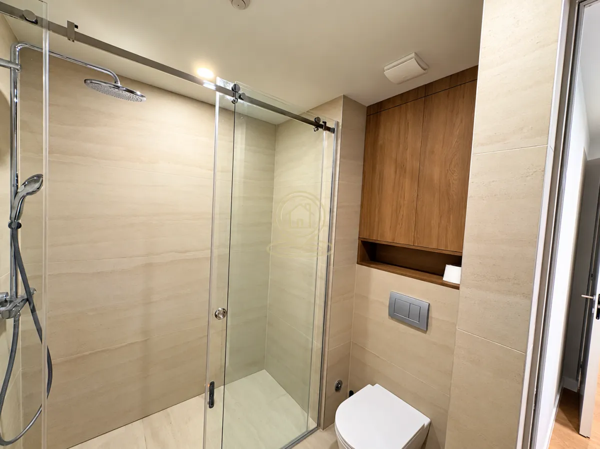 Modernly equipped bathroom with a shower cabin and built-in units.