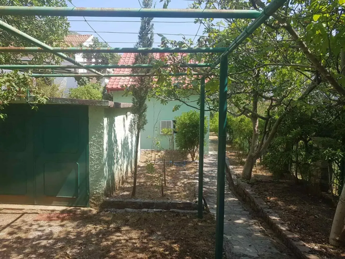 Family house yard with greenery and a covered structural frame.