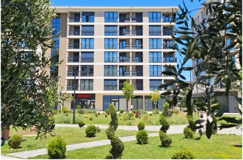 View of a modern residential building with a landscaped courtyard in the foreground. - image 6