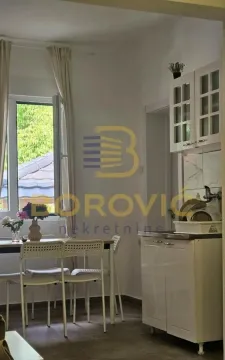 Small kitchen with white cabinets and a dining table by the window. - image 6