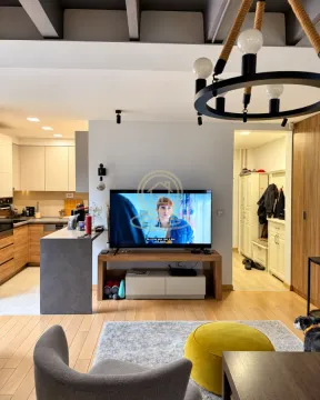 Living room with a television, comfortable armchairs, and a view of the kitchen. - image 5