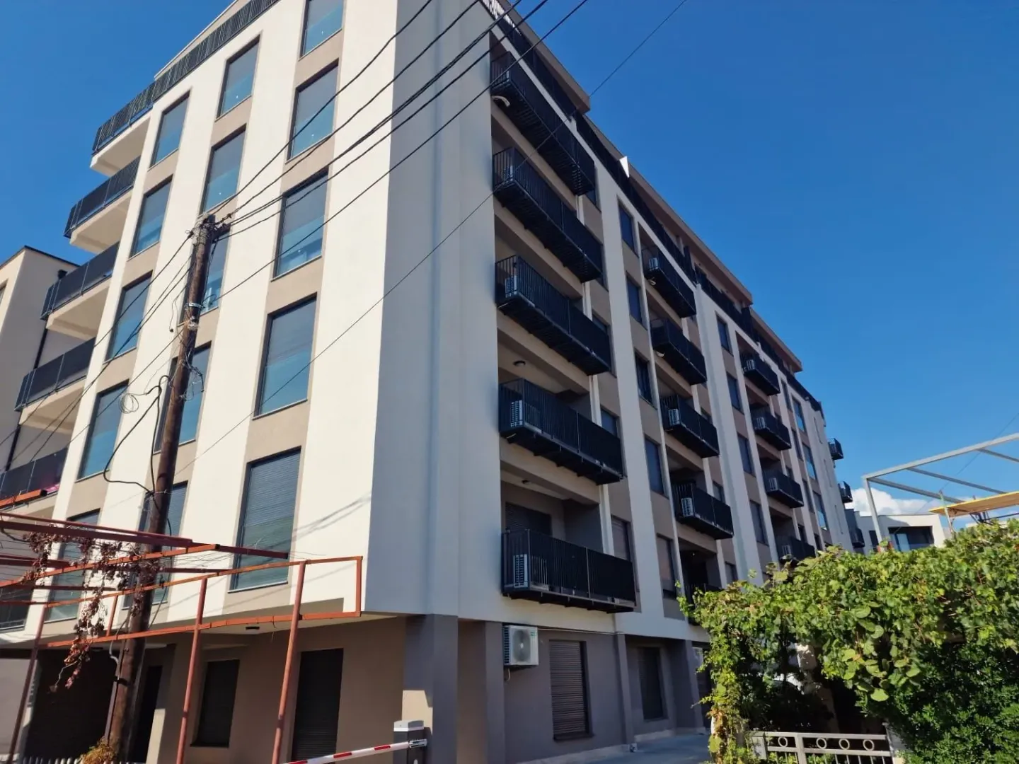 Exterior view of a residential building with balconies and a yard.