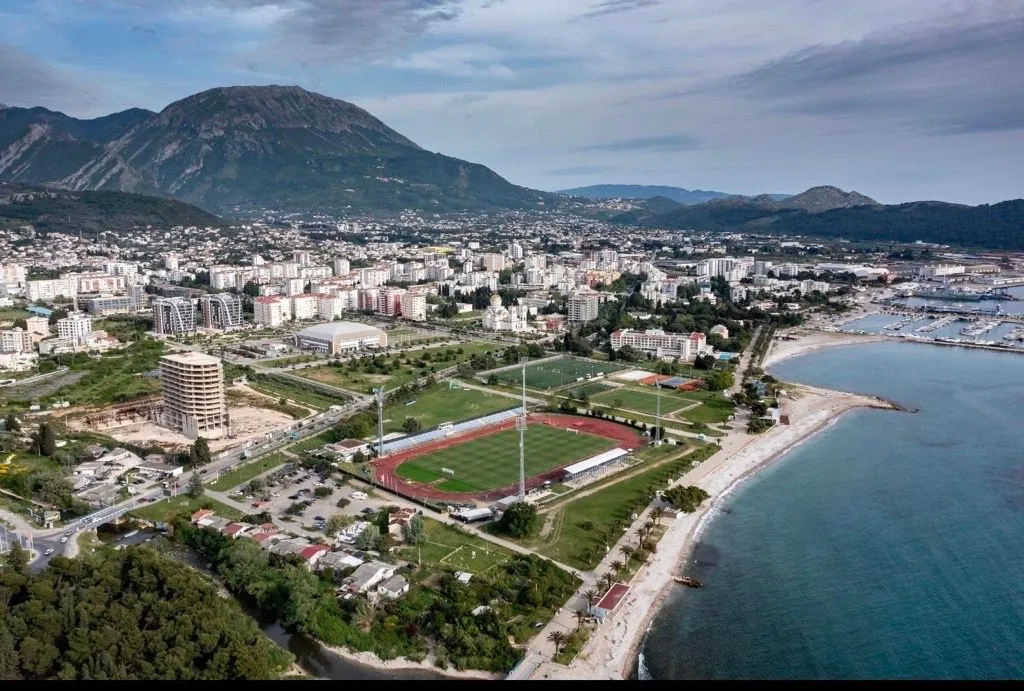 Pogled iz vazduha na grad, obalu i planine u pozadini.