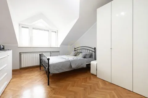 Spavaća soba u potkrovlju sa krevetom, belim ormarom i drvenim podom. - image 5