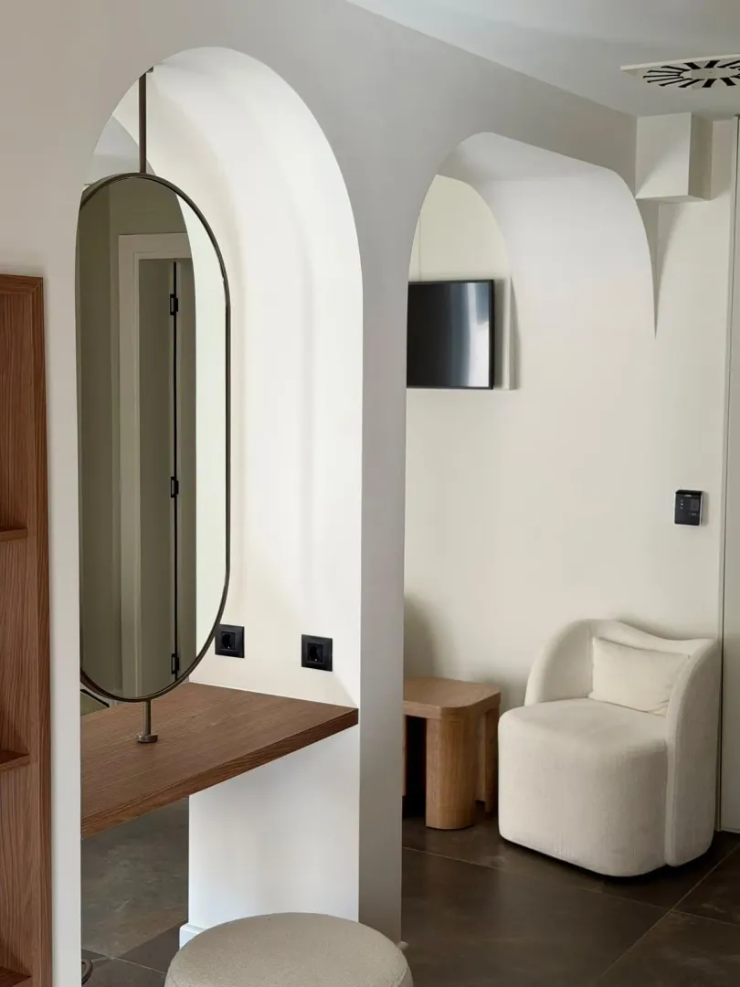 Modern interior with arches, a mirror, and an armchair.