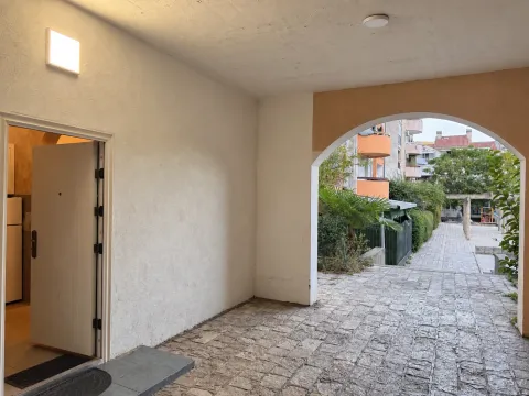 Building entrance with a paved courtyard and an open passage. - image 12