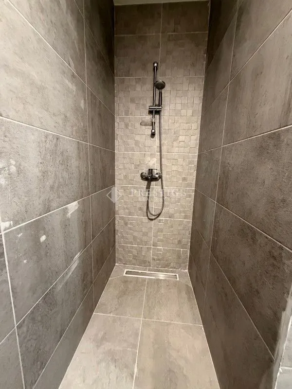Modern walk-in shower with grey tiles.