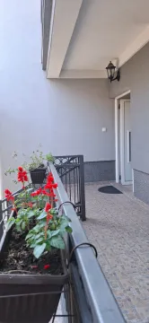 Natkriveni balkon sa metalnom ogradom i saksijama cvijeća. - image 3