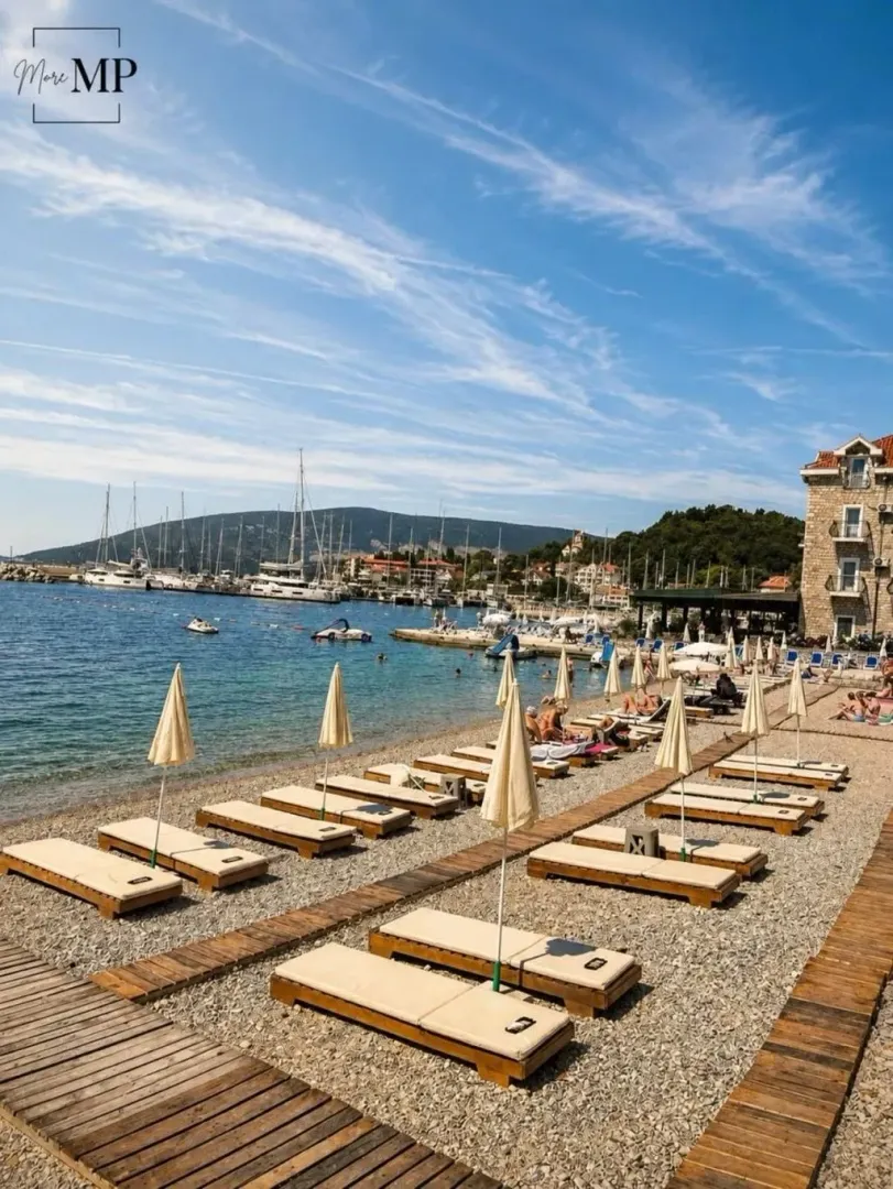 Pogled na plažu sa ležaljkama i marinom.