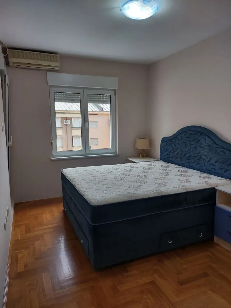 Simply furnished bedroom with a large double bed and parquet flooring.