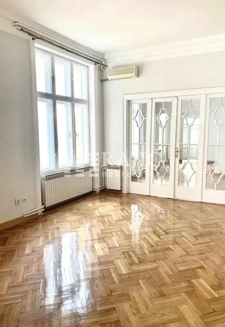 Empty room with large windows and parquet flooring.