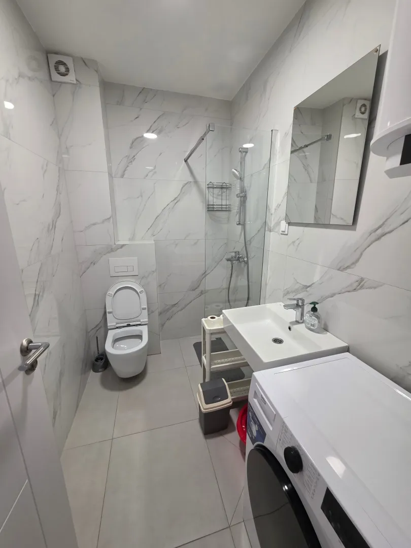 Moderne opremljeno kupatilo sa tuš kabinom, umivaonikom i veš mašinom.