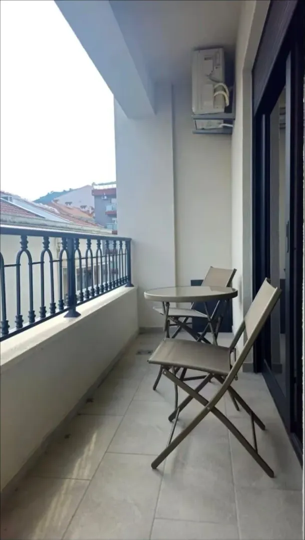 Covered balcony furnished with a small table and chairs overlooking the surroundings.