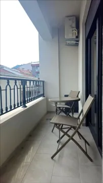 Covered balcony furnished with a small table and chairs overlooking the surroundings. - image 7