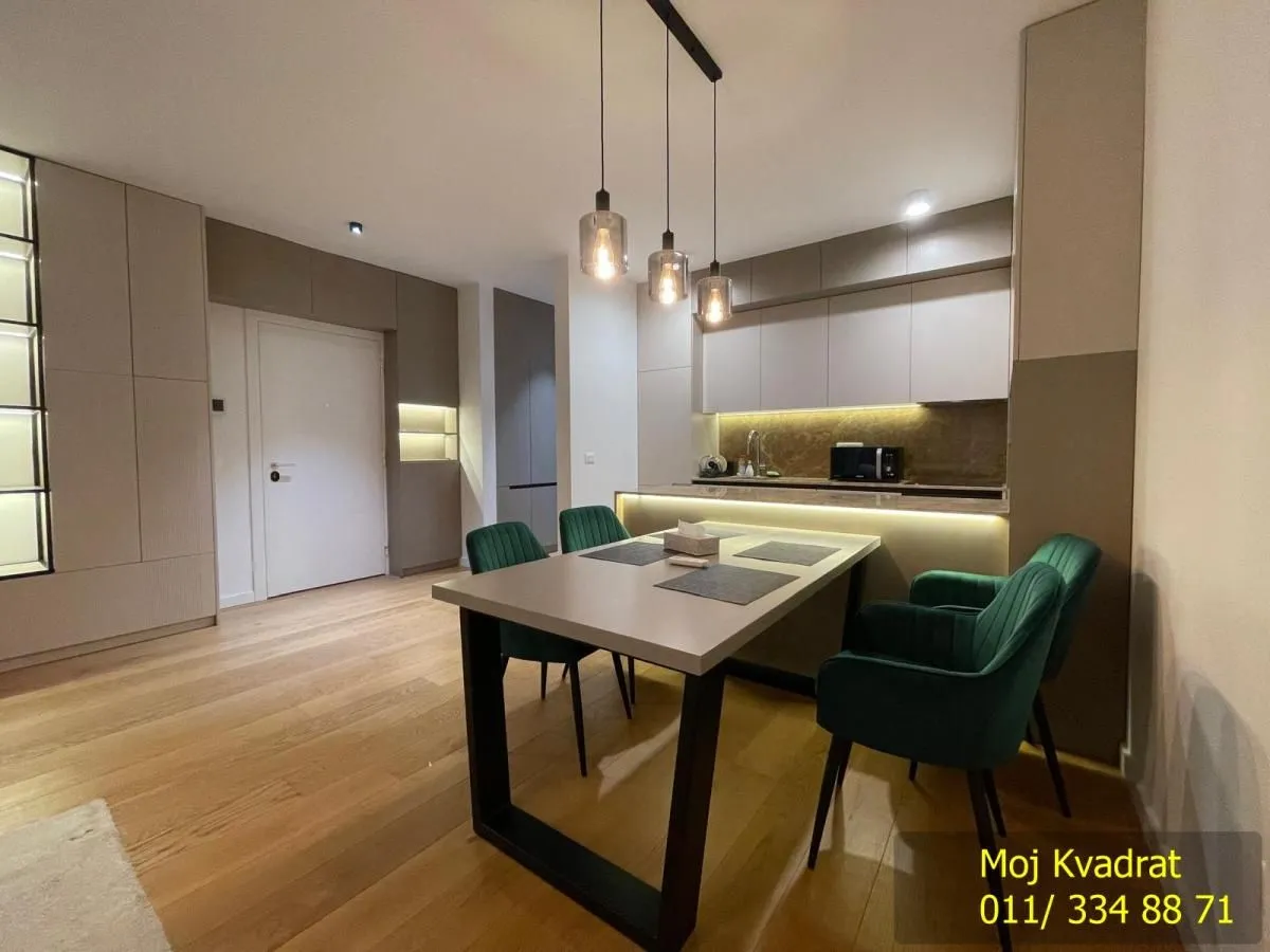 Modern kitchen with dining area and green chairs.