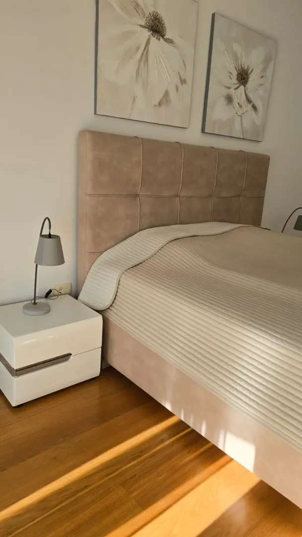 A decorated bedroom with a double bed, nightstand, and paintings on the wall.