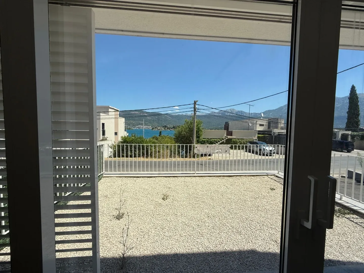 Pogled na dvorište i more kroz otvorena balkonska vrata.