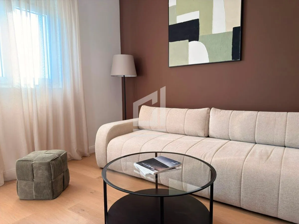 Living room with a beige sofa, coffee table, and wall artwork.