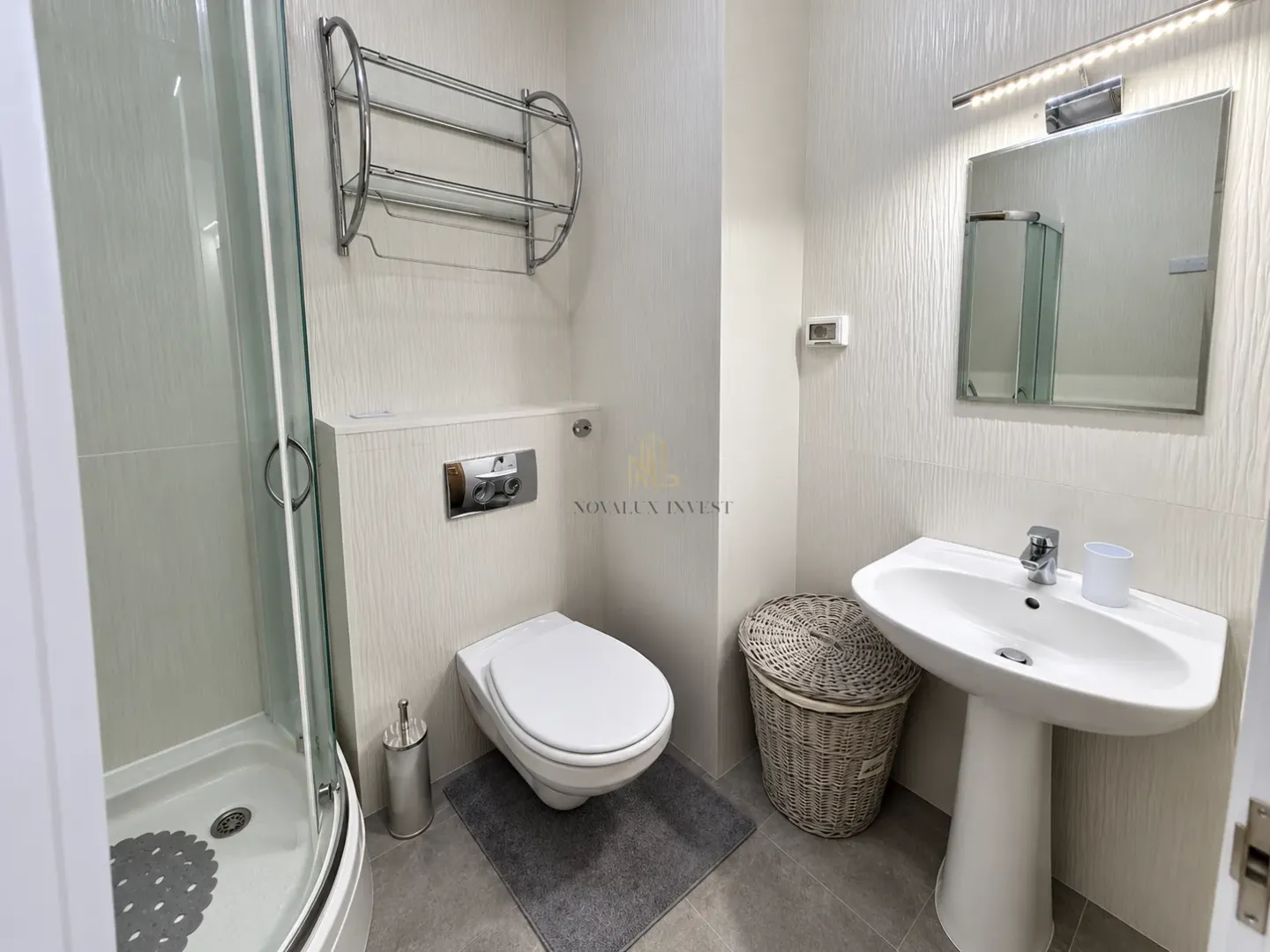 Modern bathroom with a shower cabin, washbasin, and wall-mounted toilet.