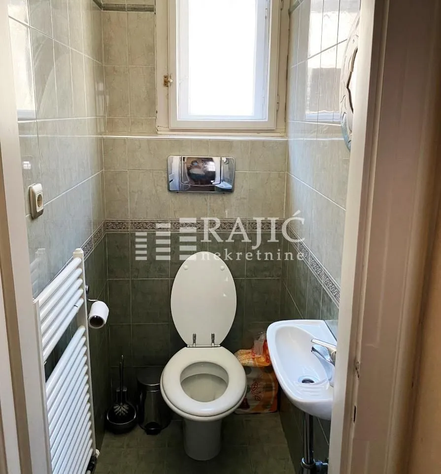 Small bathroom with a toilet, washbasin, and window.