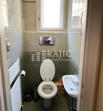 Small bathroom with a toilet, washbasin, and window. - image 12