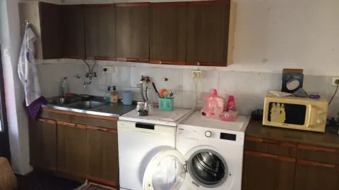 An older kitchen with wooden cabinets, a washing machine, and a microwave. - image 22