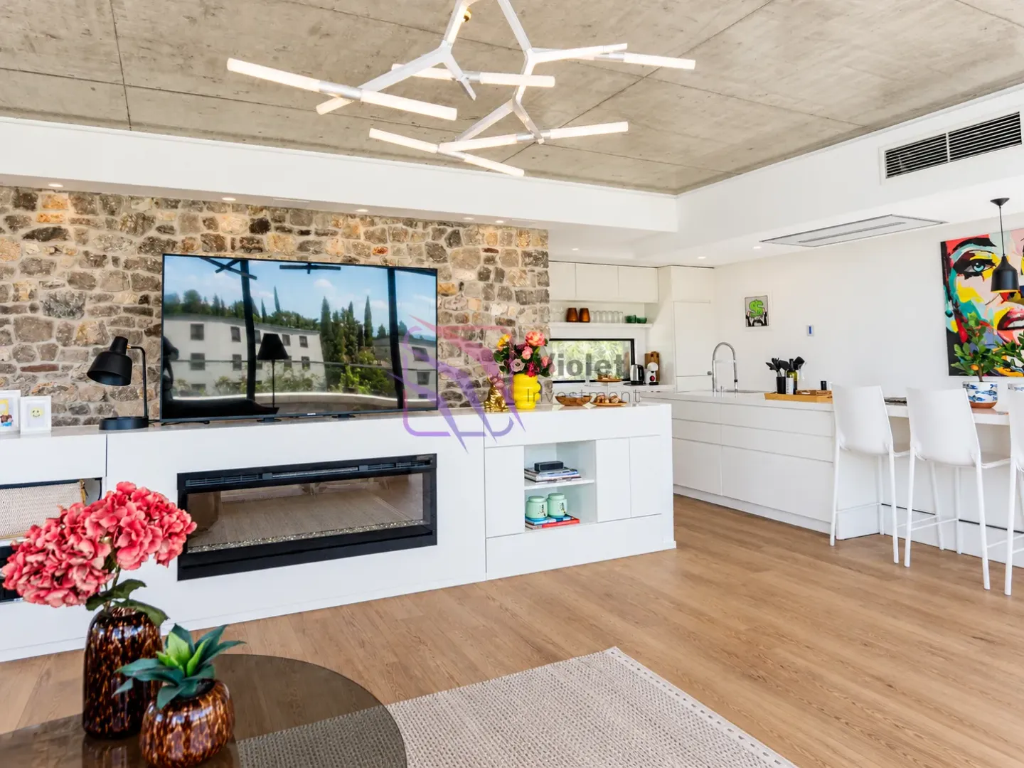 Spacious living room connected to the kitchen, featuring a stone accent wall and a modern fireplace.