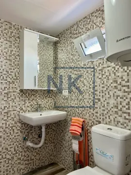 Small bathroom with a sink, toilet, water heater, and mosaic tiles. - image 2