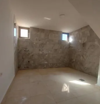 Empty bathroom tiled with ceramic tiles and featuring two small windows. - image 12