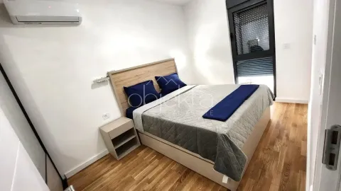 Furnished bedroom with a double bed, bedside table, and air conditioning unit. - image 9