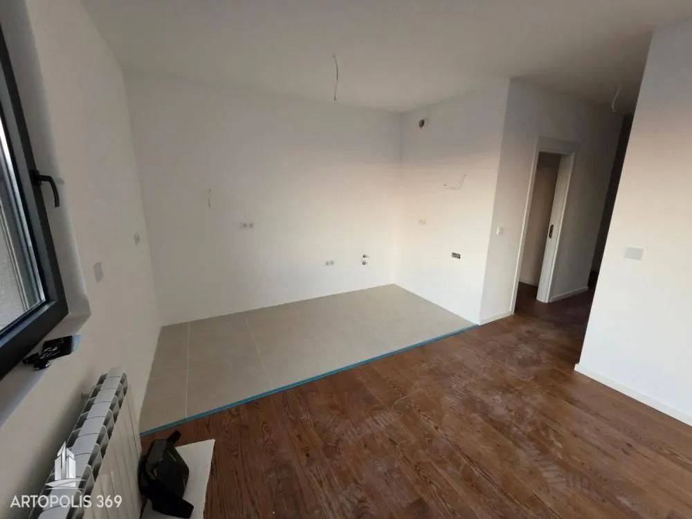 Empty room with combined tile and parquet flooring.