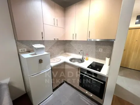 Small equipped kitchen with a white refrigerator and built-in units. - image 4