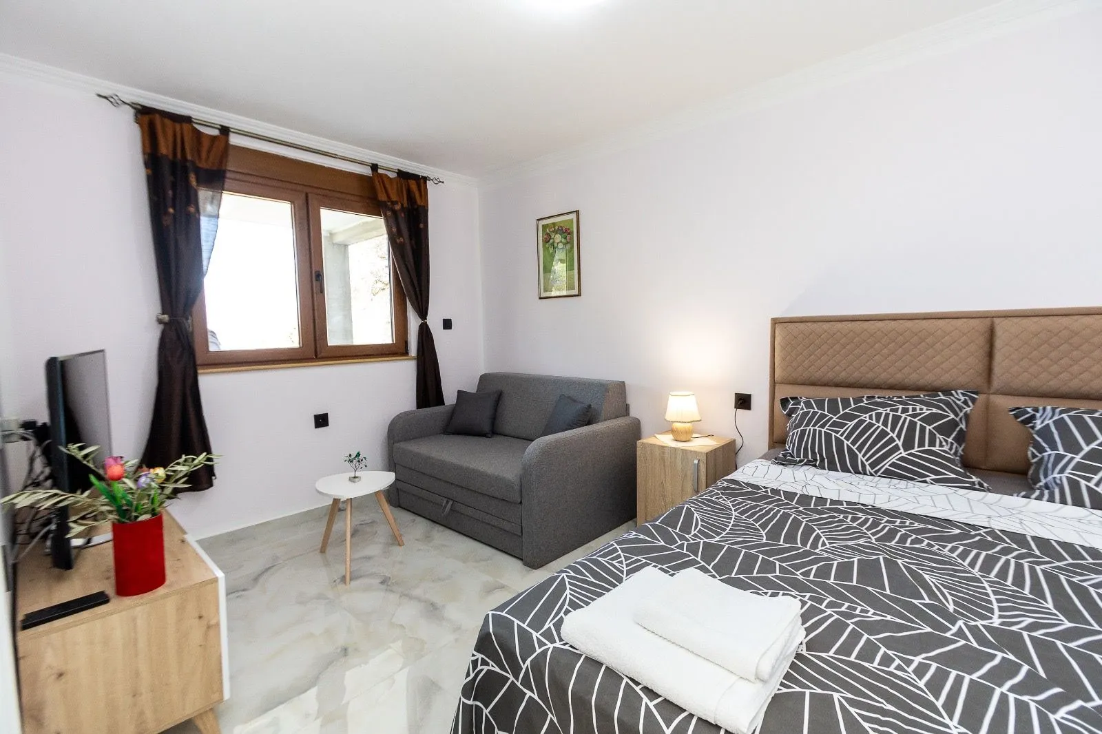 Furnished bedroom with a double bed, pull-out sofa, and window.