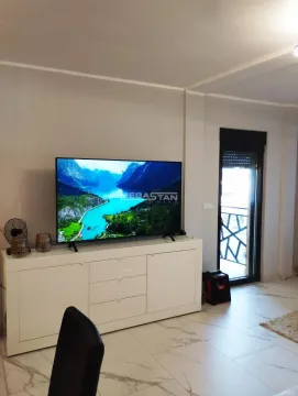 Dnevna soba sa televizorom na beloj komodi i izlazom na terasu. - image 2