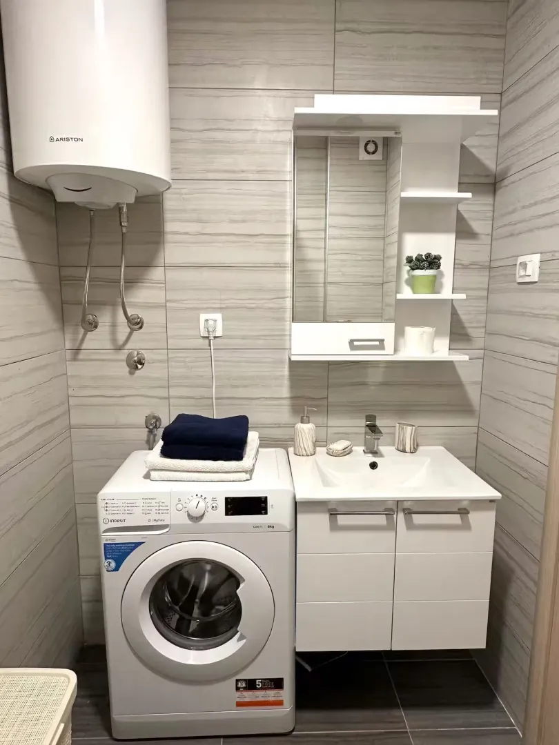 Modernly equipped bathroom with a washbasin, washing machine, and water heater.
