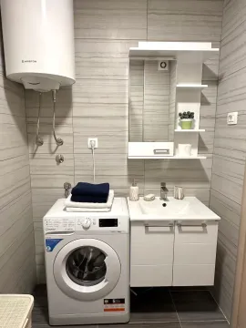 Modernly equipped bathroom with a washbasin, washing machine, and water heater. - image 14
